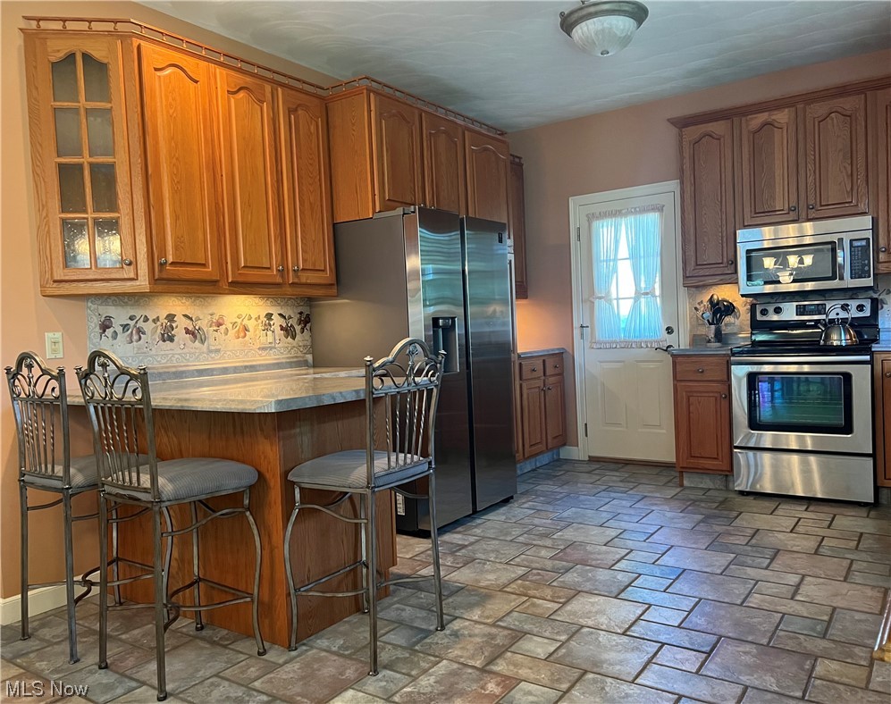 185 B Mathews Road Youngstown, OH 44512 - Photo 17 of 35 Kitchen with appliances with stainless steel finishes, backsplash, a kitchen island, and light tile flooring