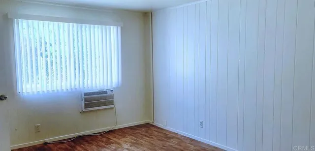 an empty room with wooden floor and windows with curtains