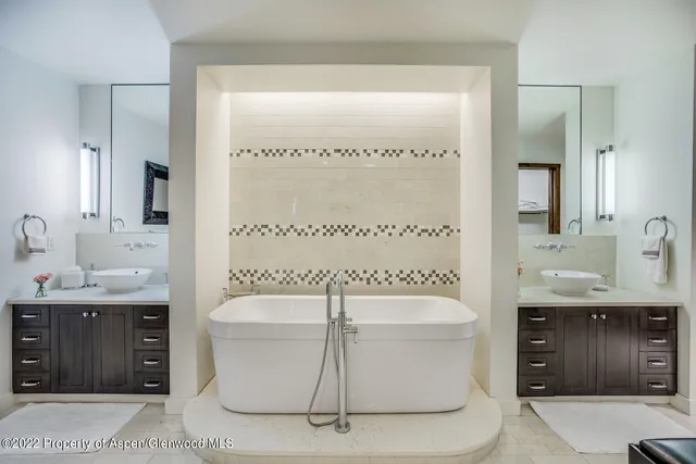 a bathroom with a tub a sink and a mirror