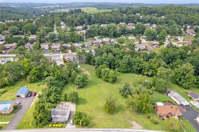 an aerial view of residential houses with outdoor space and trees