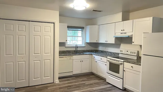 a kitchen with granite countertop white cabinets and white appliances