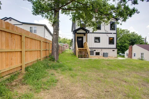 a view of a yard in front of a house with large trees