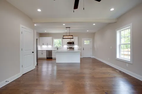 an open kitchen with kitchen island a sink dishwasher stove and white cabinets with wooden floor