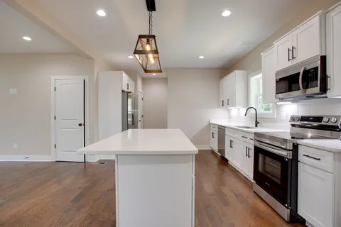 a kitchen with stainless steel appliances granite countertop a sink a stove and a wooden floors
