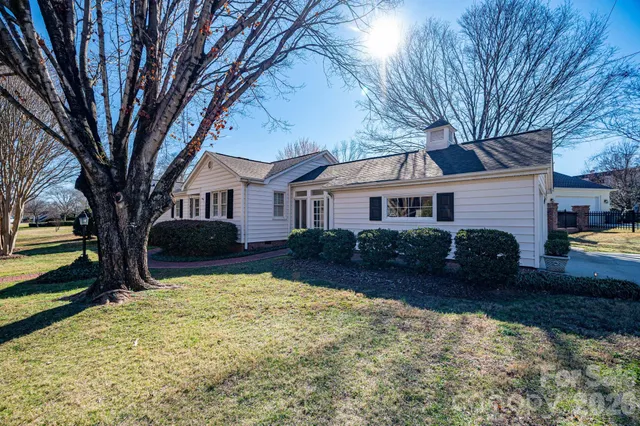 a front view of a house with a yard and a large tree