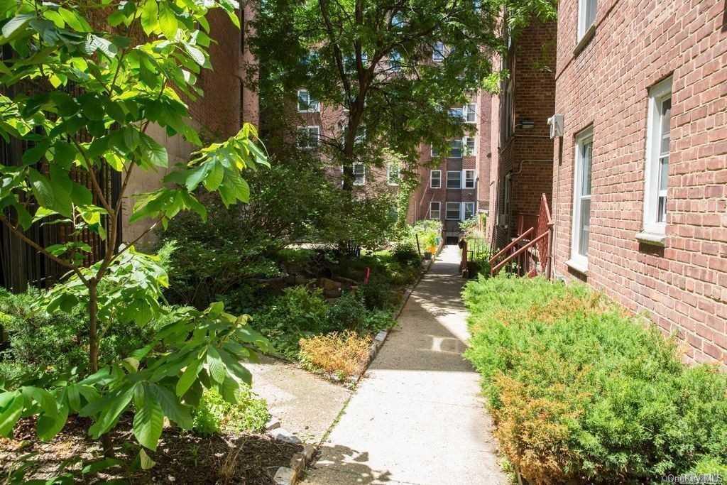 34-10 75th Street, Unit K2 Queens, NY 11372 - Photo 14 of 16 a view of a pathway with plants and large trees