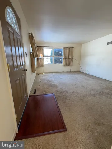 an empty room with windows and chandelier fan