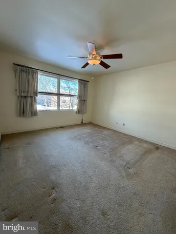 an empty room with a chandelier fan and windows