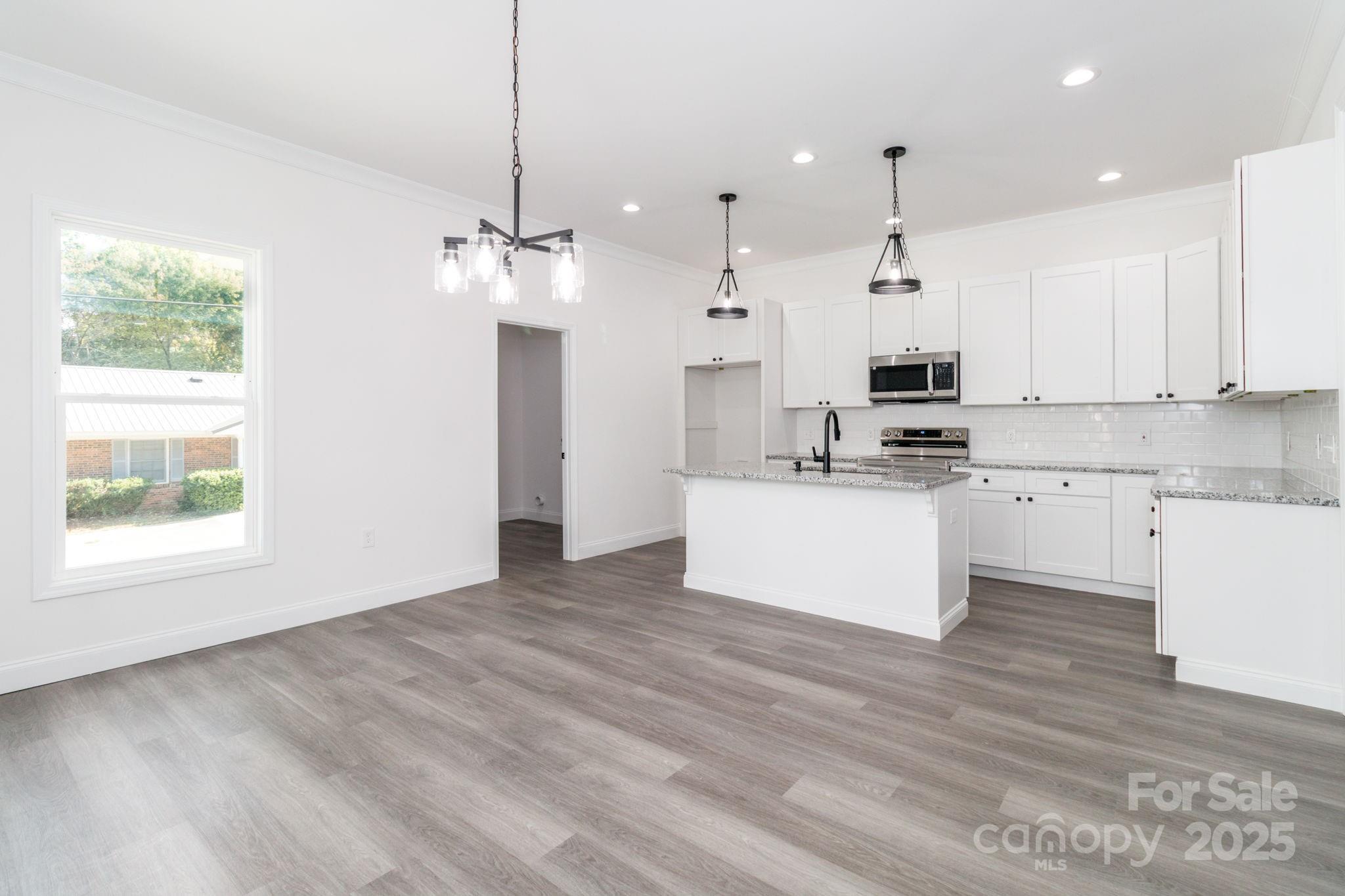 307 East Arch Street Lancaster, SC 29720 - Photo 13 of 43 a large kitchen with stainless steel appliances kitchen island a white cabinets and a chandelier