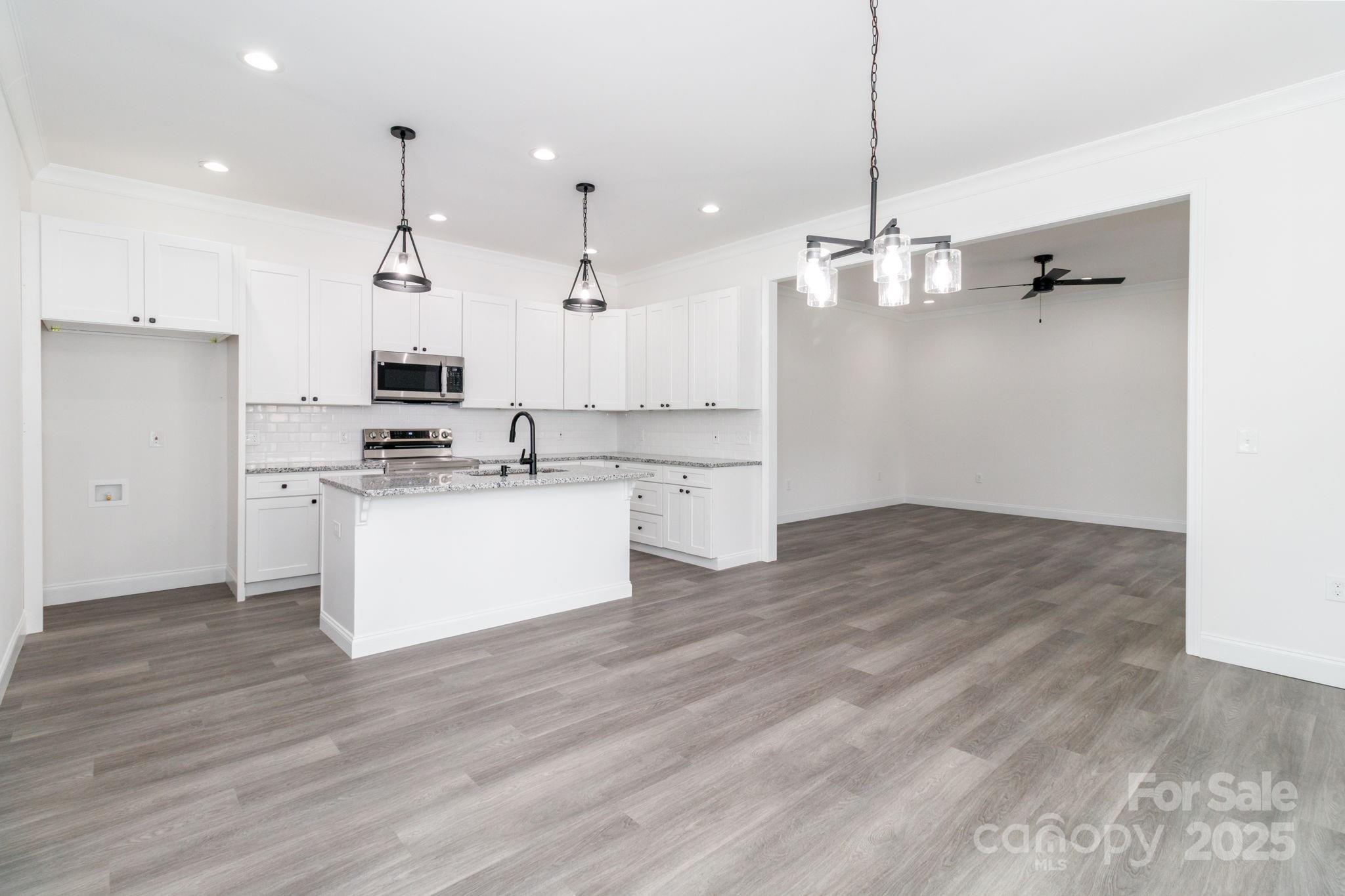 307 East Arch Street Lancaster, SC 29720 - Photo 15 of 43 a kitchen with kitchen island white cabinets stainless steel appliances and wooden floor