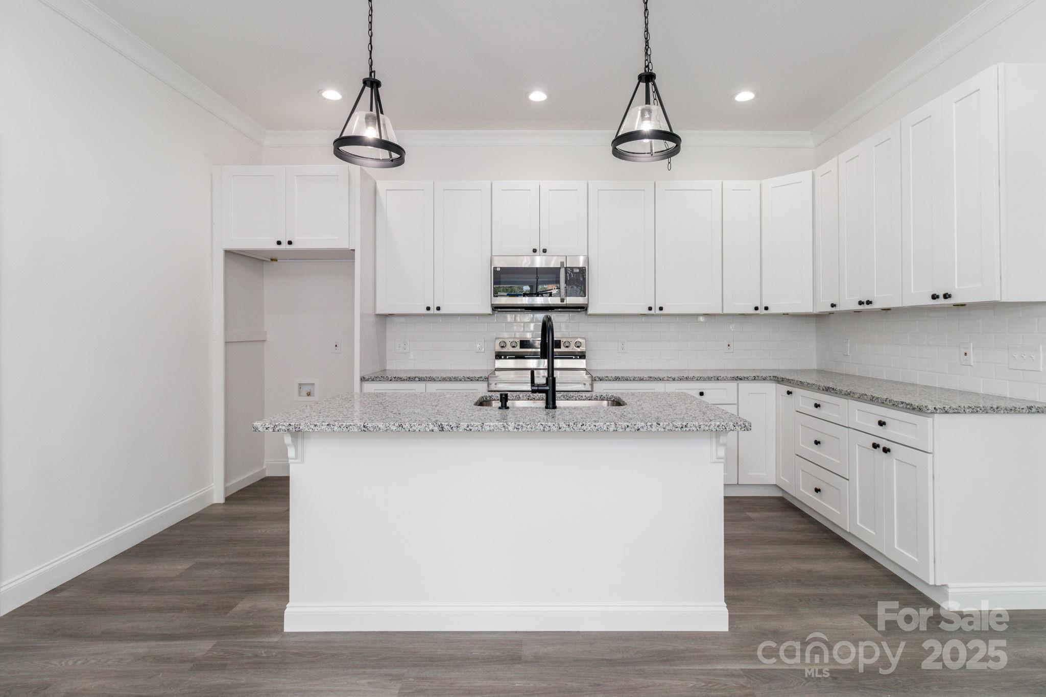 307 East Arch Street Lancaster, SC 29720 - Photo 16 of 43 a kitchen with kitchen island granite countertop a sink a counter space appliances and cabinets