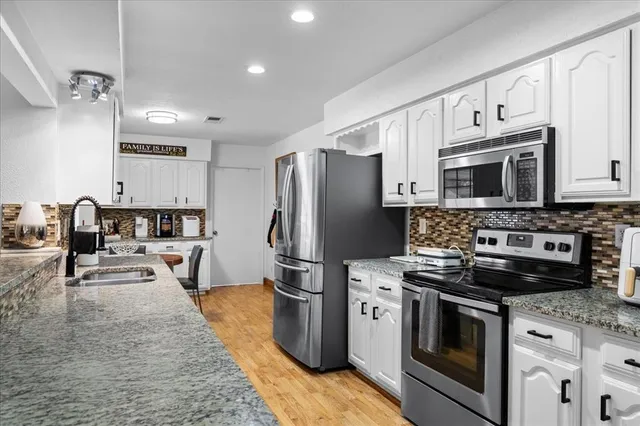 a kitchen with stainless steel appliances a stove refrigerator sink and microwave
