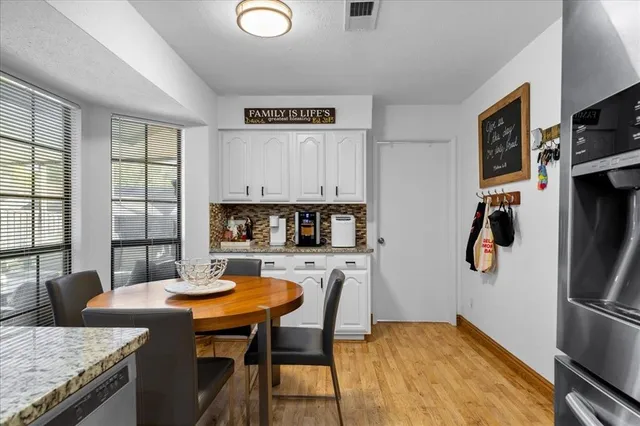 a kitchen with stainless steel appliances granite countertop a stove a refrigerator a kitchen island a dining table and chairs with wooden floor