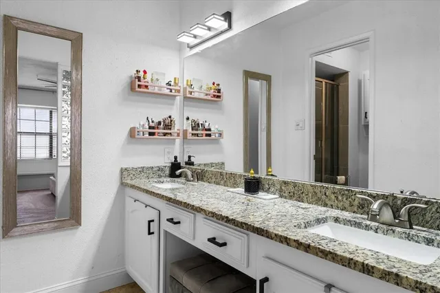 a bathroom with a granite countertop double vanity and a mirror