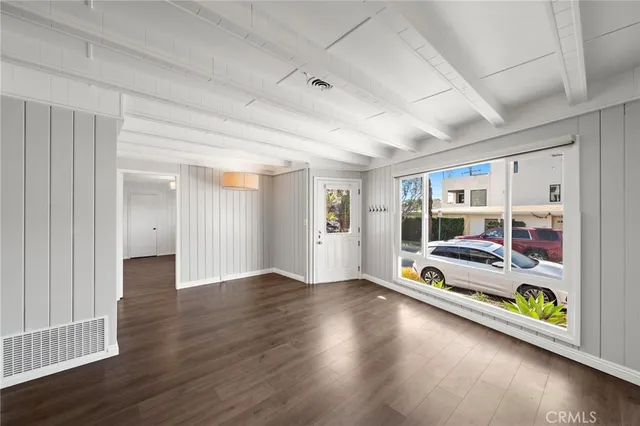 a view of an empty room with window and wooden floor