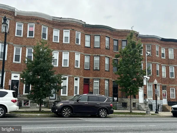 a front view of a building with lot of cars and trees