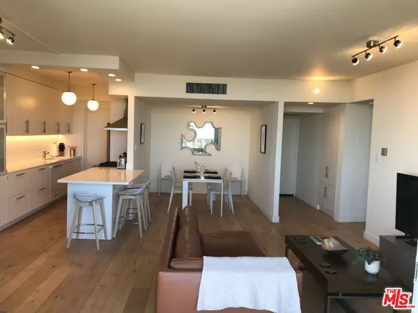 a living room with furniture a flat screen tv and a view of kitchen