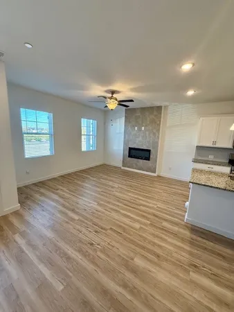 an empty room with wooden floor fireplace and windows