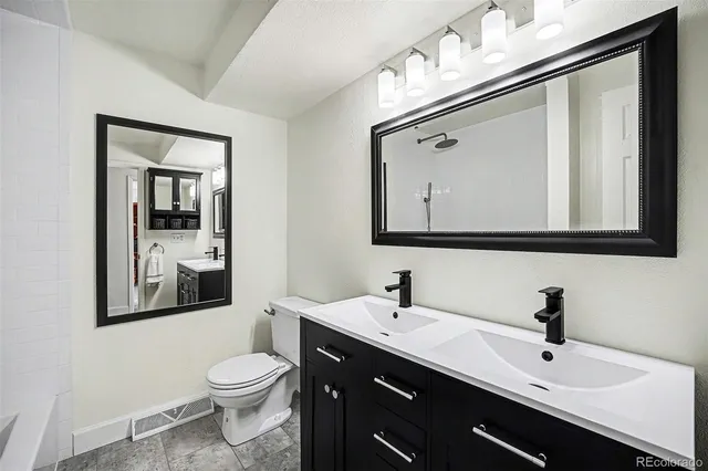 a bathroom with a toilet sink double vanity and mirror
