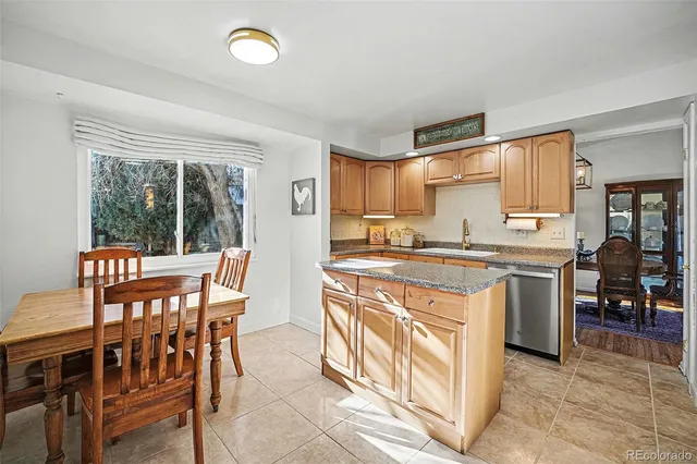a kitchen with stainless steel appliances granite countertop a stove top oven a sink a dining table and chairs