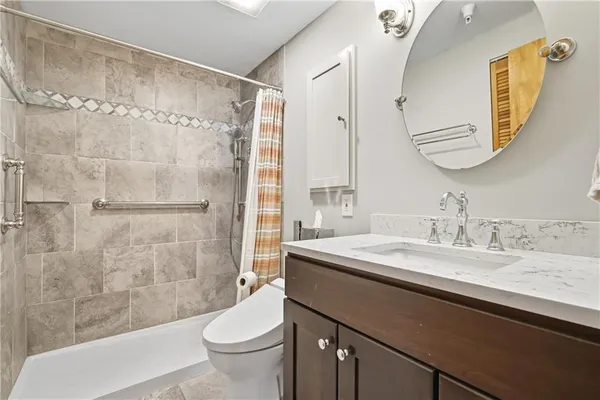 a bathroom with a granite countertop sink a toilet a mirror and shower
