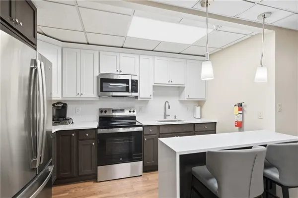 a kitchen with stainless steel appliances a stove a sink dishwasher a refrigerator white cabinets and wooden floor