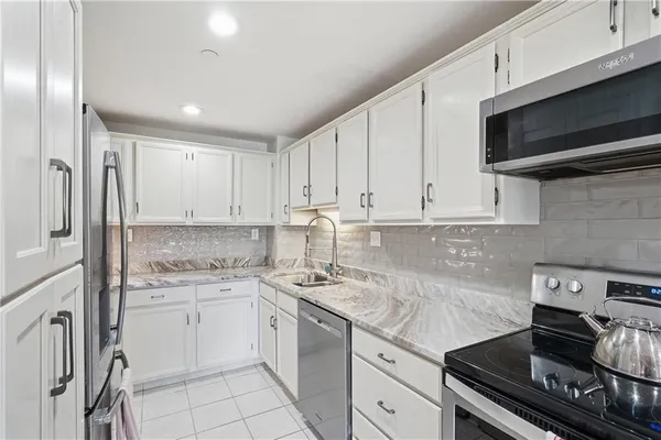 a kitchen with stainless steel appliances granite countertop a sink stove a oven and white cabinets