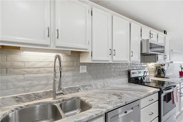 a kitchen with stainless steel appliances granite countertop a sink a stove and cabinets