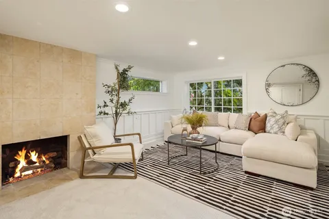a living room with furniture a fireplace and a floor to ceiling window