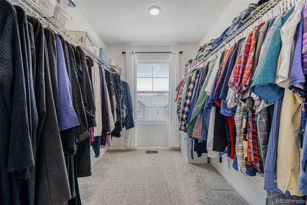 a view of walk in closet with clothes and shoes