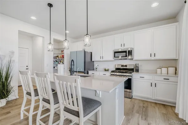 a kitchen that has a lot of white cabinets and stainless steel appliances