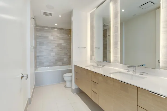 a bathroom with a double vanity sink toilet mirror and bathtub