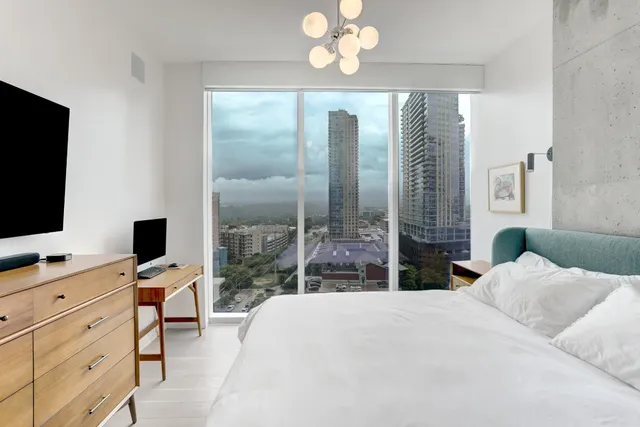 a bedroom with a large bed and a flat tv screen on dresser