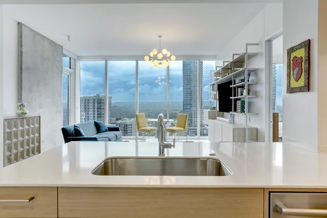 a kitchen counter with a sink and large mirror