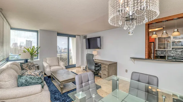 a living room with furniture a chandelier and a flat screen tv