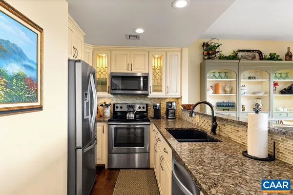 a kitchen with stainless steel appliances granite countertop a stove a sink and a refrigerator