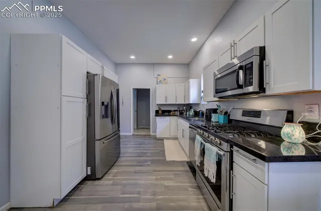 a kitchen with granite countertop a refrigerator and a stove top oven