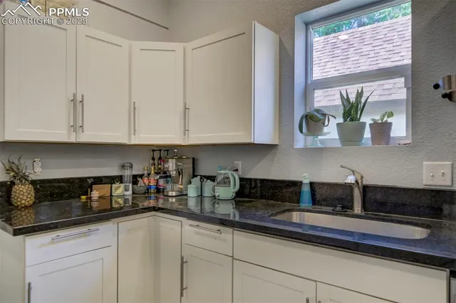 a kitchen with stainless steel appliances granite countertop white cabinets sink and window