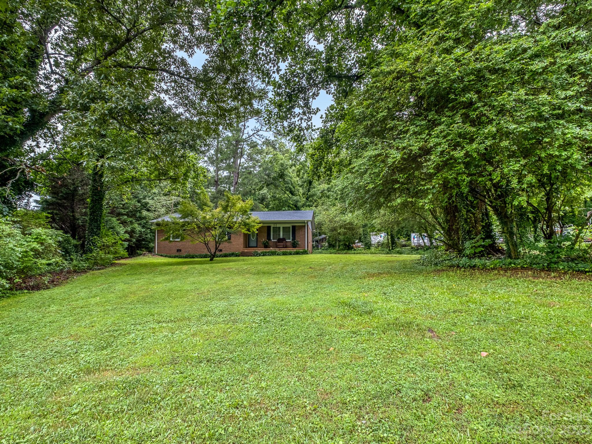 648 Blacksnake Road Stanley, NC 28164 - Photo 5 of 24 a yellow house in middle of the forest