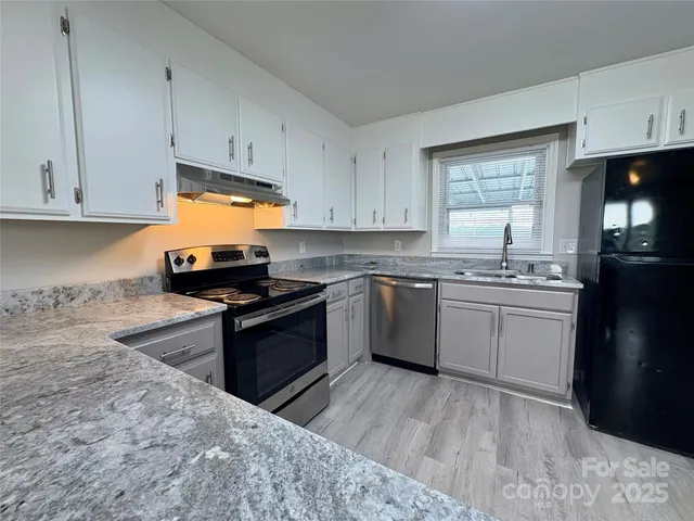 a kitchen with granite countertop a sink stainless steel appliances and cabinets