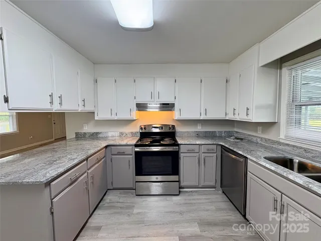 a kitchen with granite countertop stainless steel appliances and white cabinets