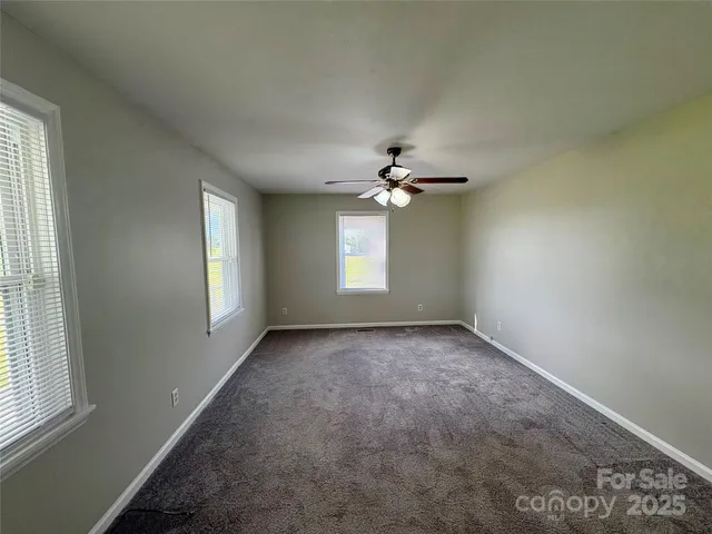 an empty room with windows and chandelier fan