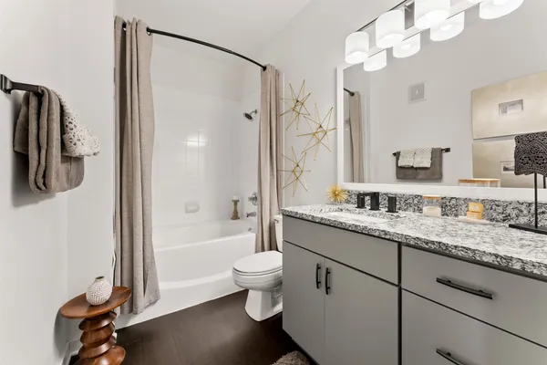 a bathroom with a granite countertop sink a toilet a mirror and shower