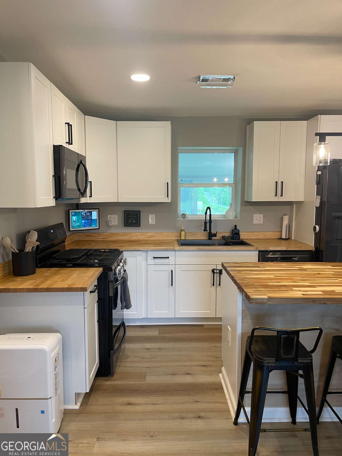 433 Spring Place Resaca Road Chatsworth, GA 30705 - Photo 21 of 60 a kitchen with stainless steel appliances granite countertop a stove a sink dishwasher a microwave oven and a refrigerator with wooden cabinets