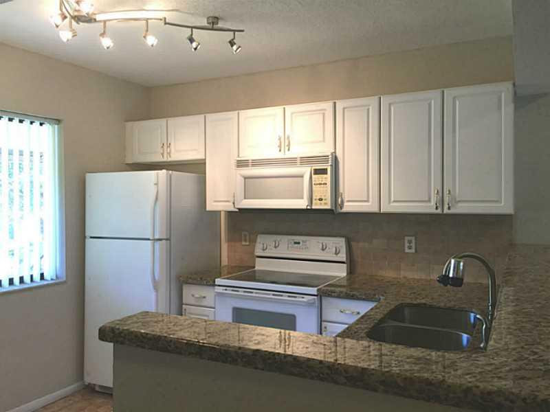 21955 Tidewater Terrace, Unit 208 Boca Raton, FL 33433 - Photo 5 of 26 a kitchen with kitchen island granite countertop a sink stainless steel appliances and cabinets