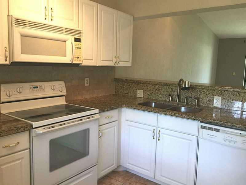 21955 Tidewater Terrace, Unit 208 Boca Raton, FL 33433 - Photo 6 of 26 a kitchen with granite countertop white cabinets white appliances and a sink