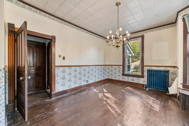 a view of a livingroom with a chandelier curtains and wooden floor