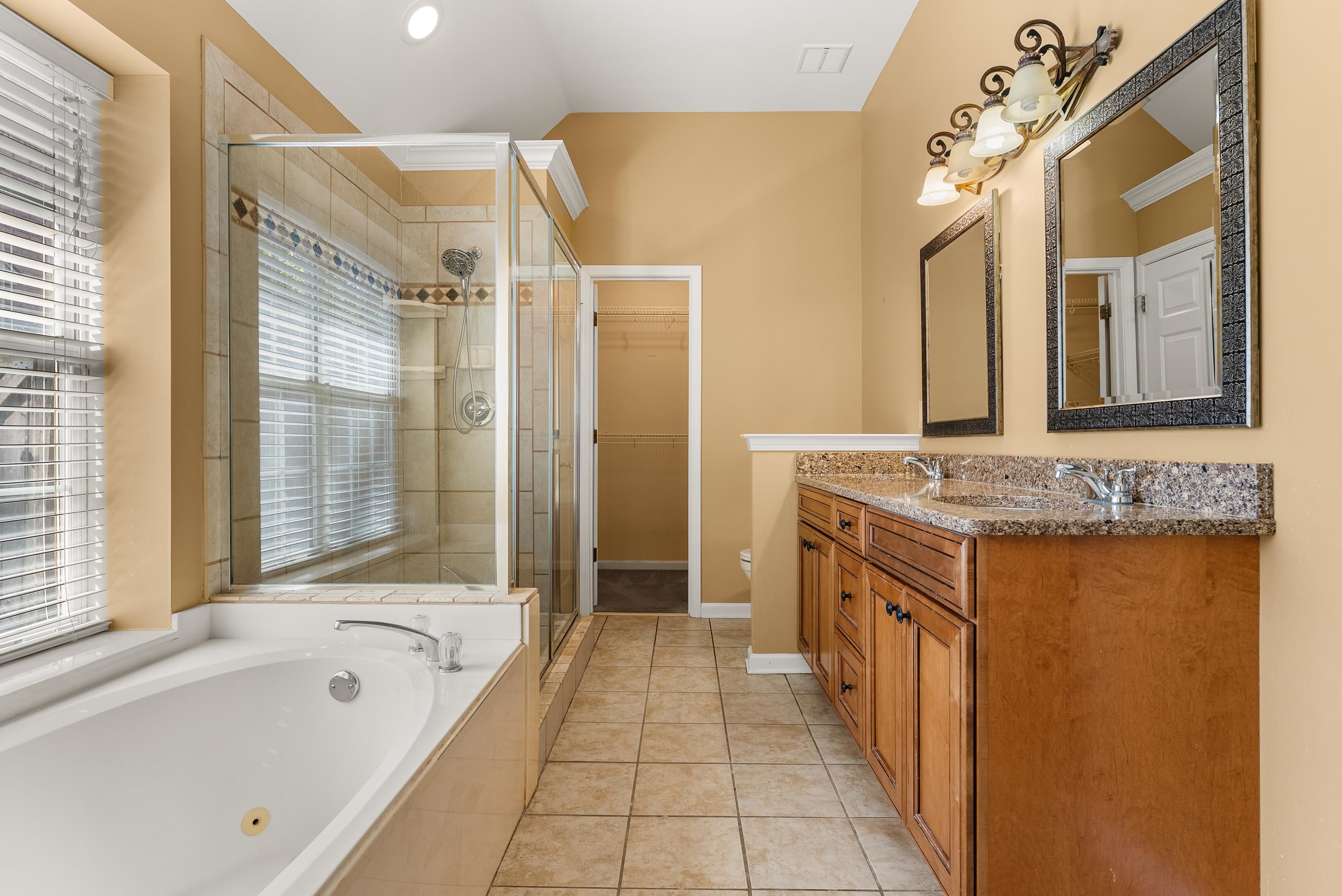 978 Sugar Lane Collierville, TN 38017 - Photo 8 of 14 a bathroom with a granite countertop sink a mirror a bathtub and shower