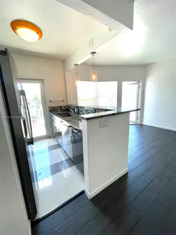 a view of a big room with wooden floor kitchen view and windows