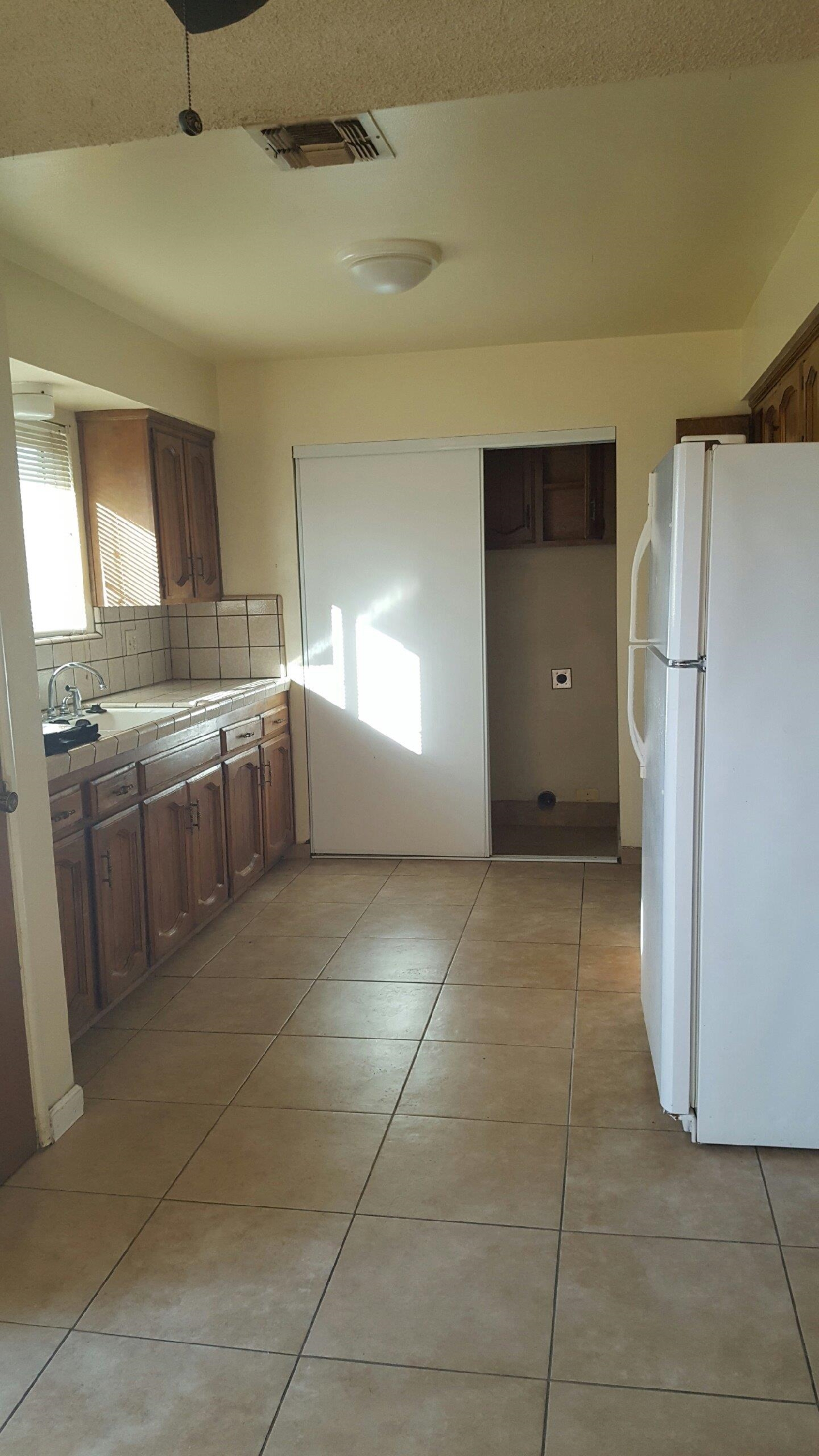 1235 C Street Reedley, CA 93654 - Photo 4 of 8 a large white kitchen with cabinets and a refrigerator